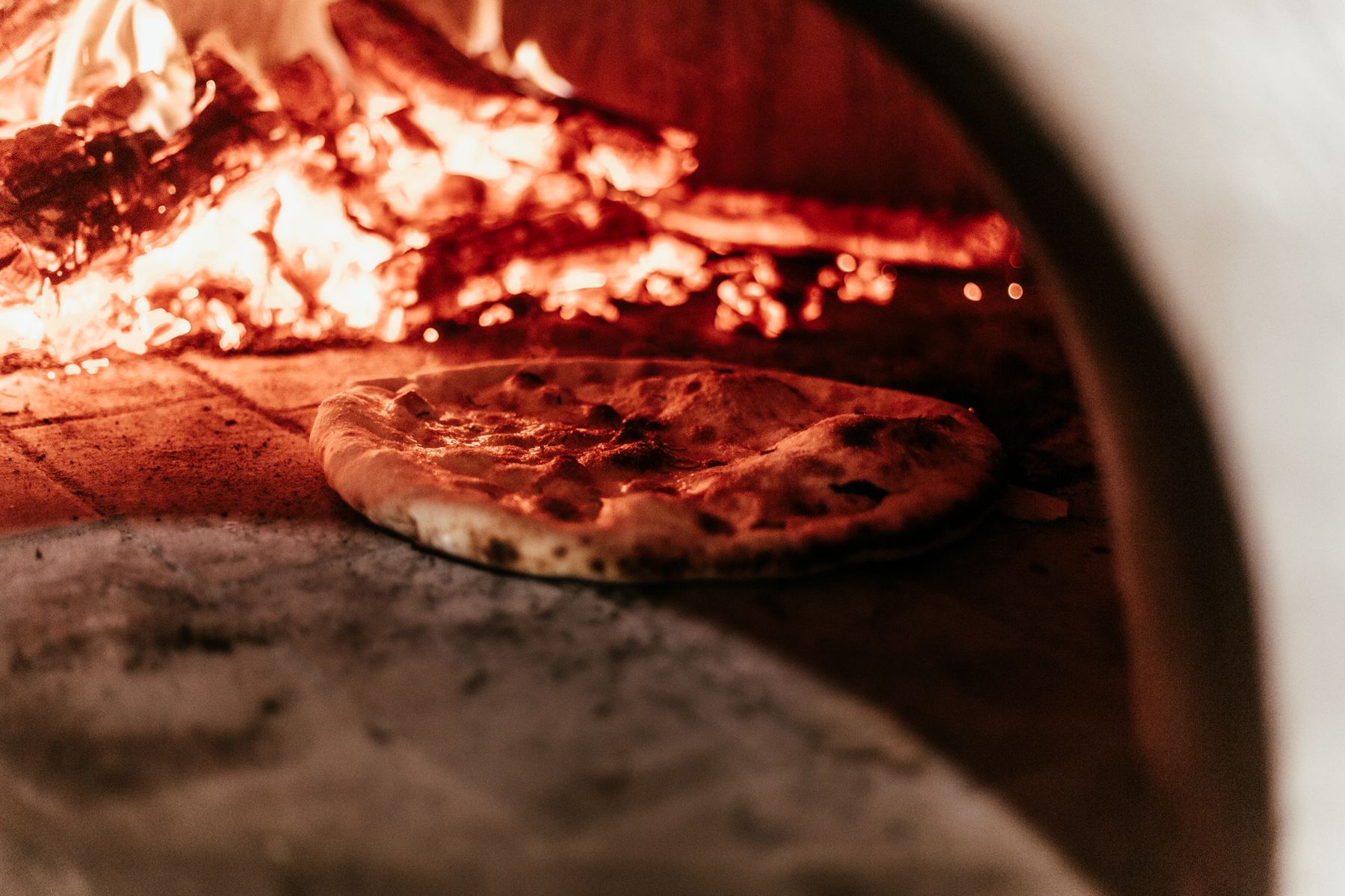 A pizza baking in a wood fired oven