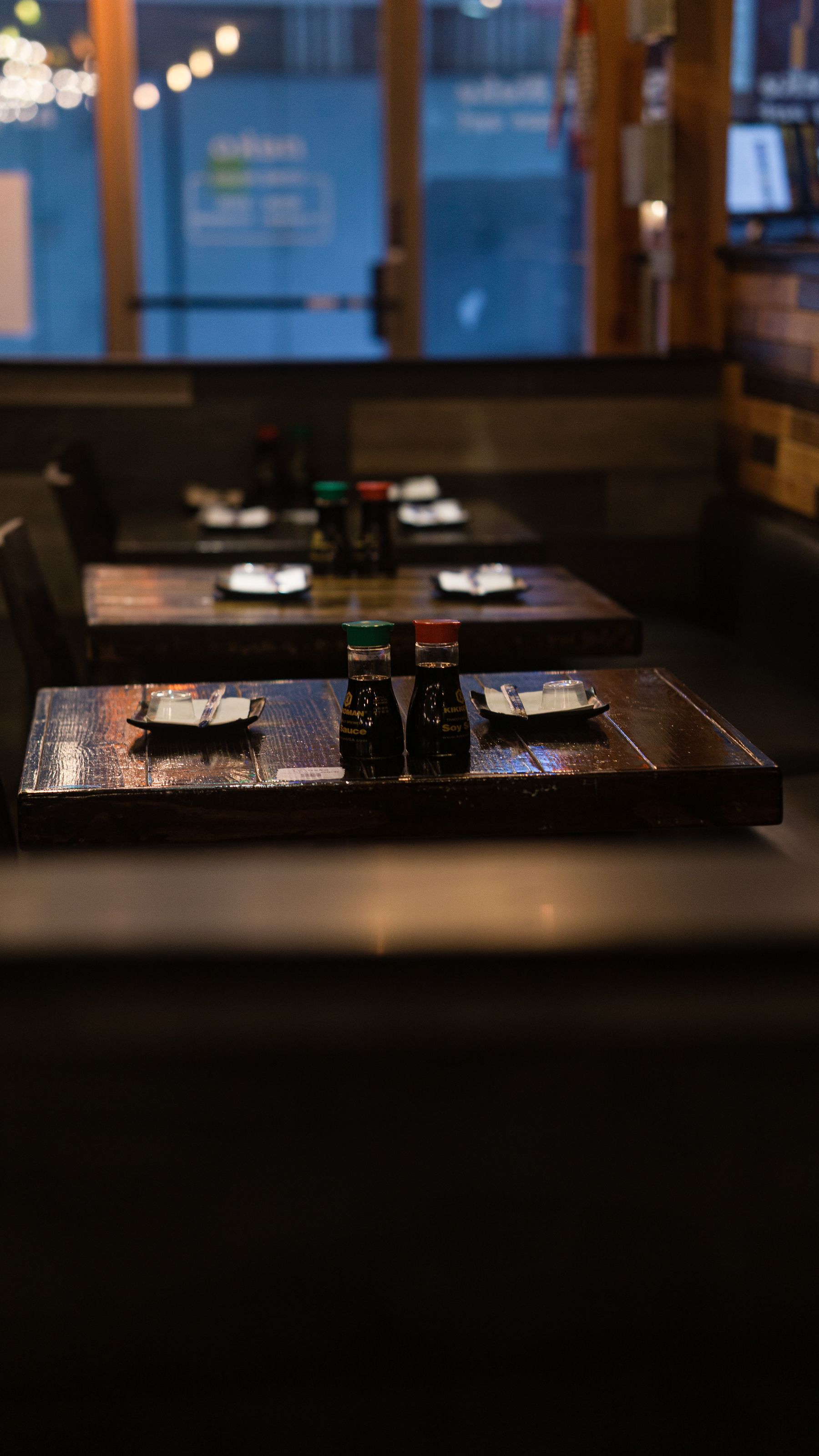 Wooden tables set for service in a warmly lit restaurant